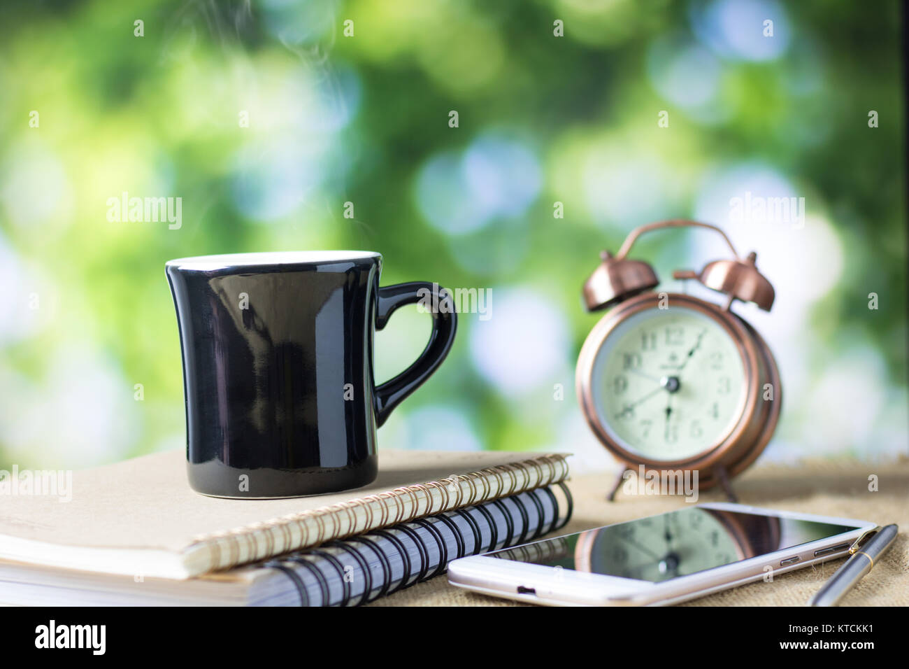 Vaso de café sobre la mesa con el libro y el reloj por la mañana Foto de stock