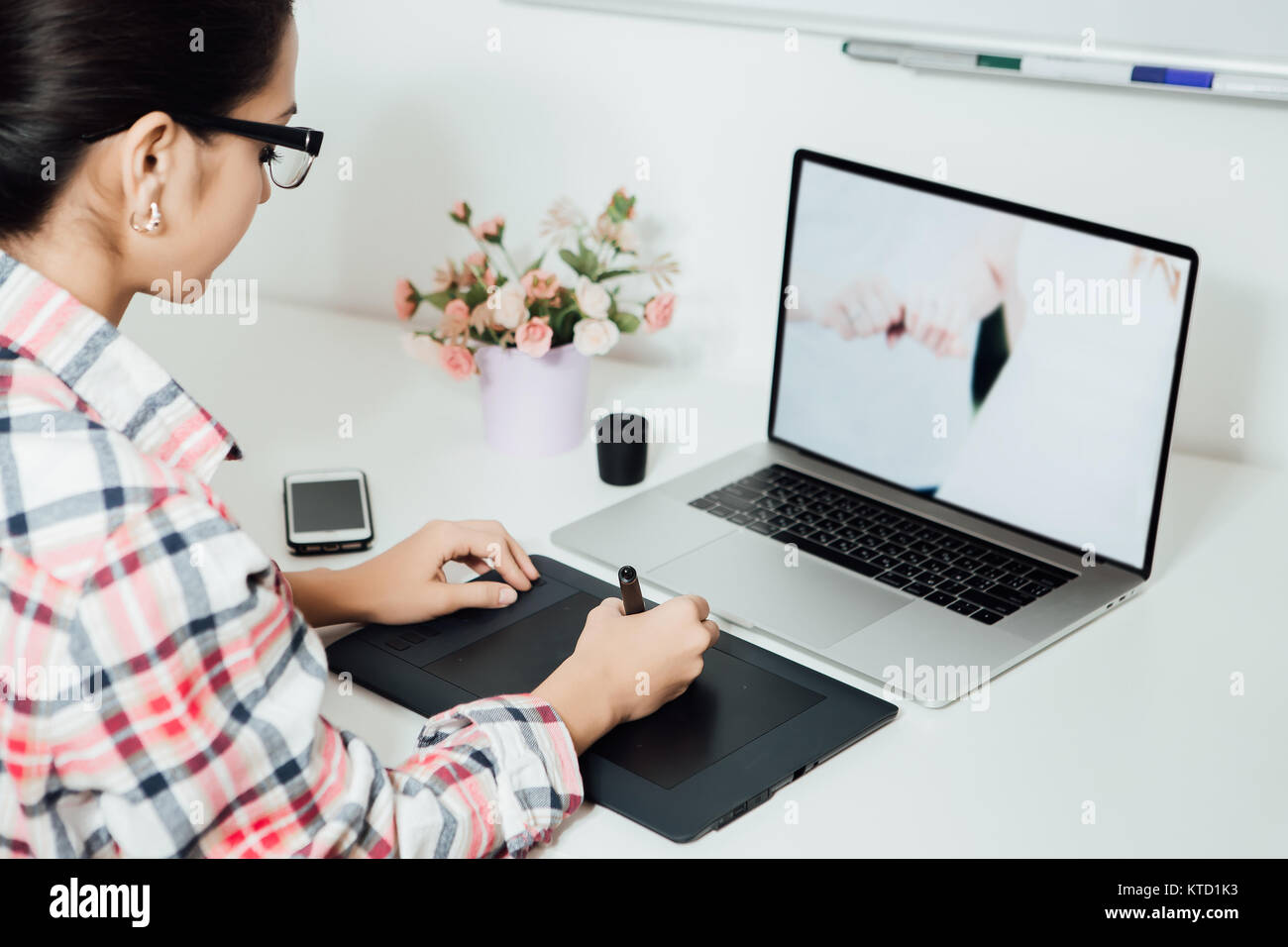 Mujer retoque en el ordenador portátil y tableta digital mediante lápiz óptico Foto de stock
