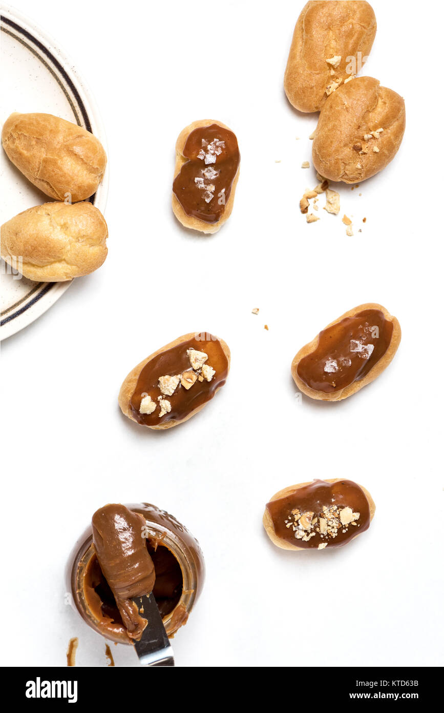 Caramelo salado eclairs bañadas en un ambiente oscuro. Foto de stock