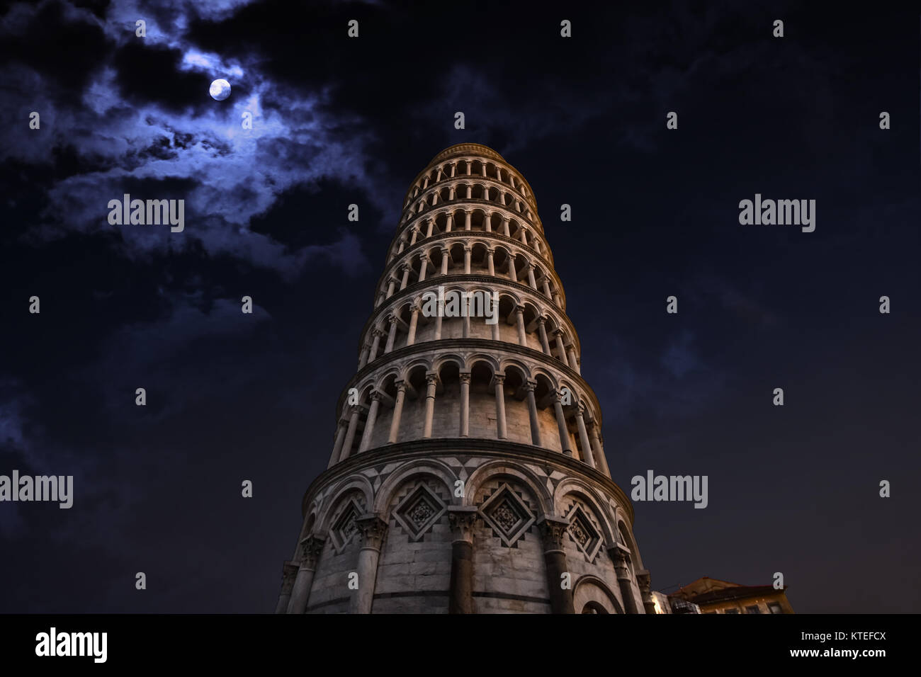 La torre inclinada de Pisa, Italia, en la Plaza de los Milagros, iluminado durante la noche con una luna llena detrás Foto de stock
