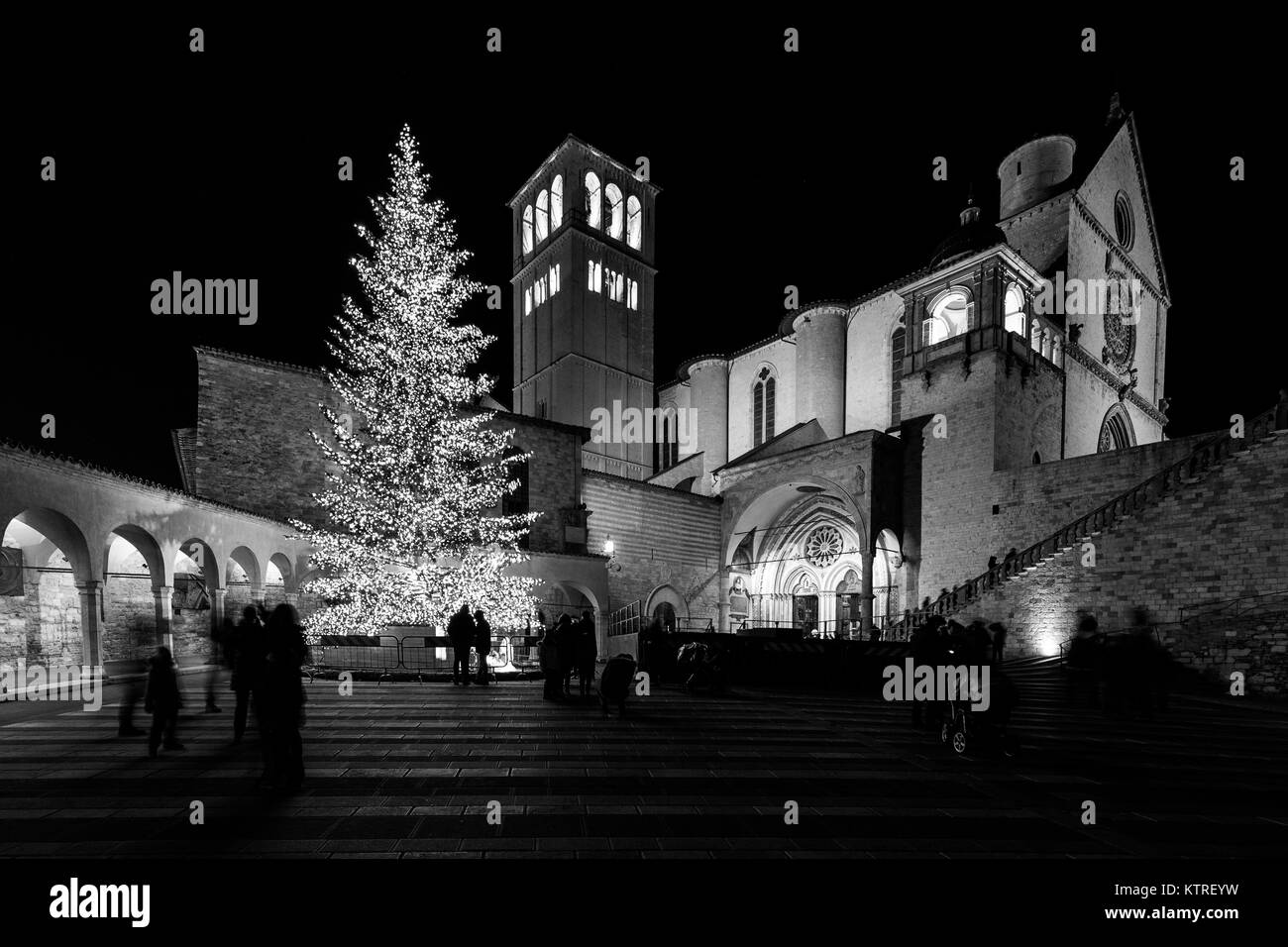 Navidad 2017 en Asís (Umbría), con una vista de San Francisco, Iglesia papal por la noche, con grandes árboles iluminados y la gente en la plaza Foto de stock