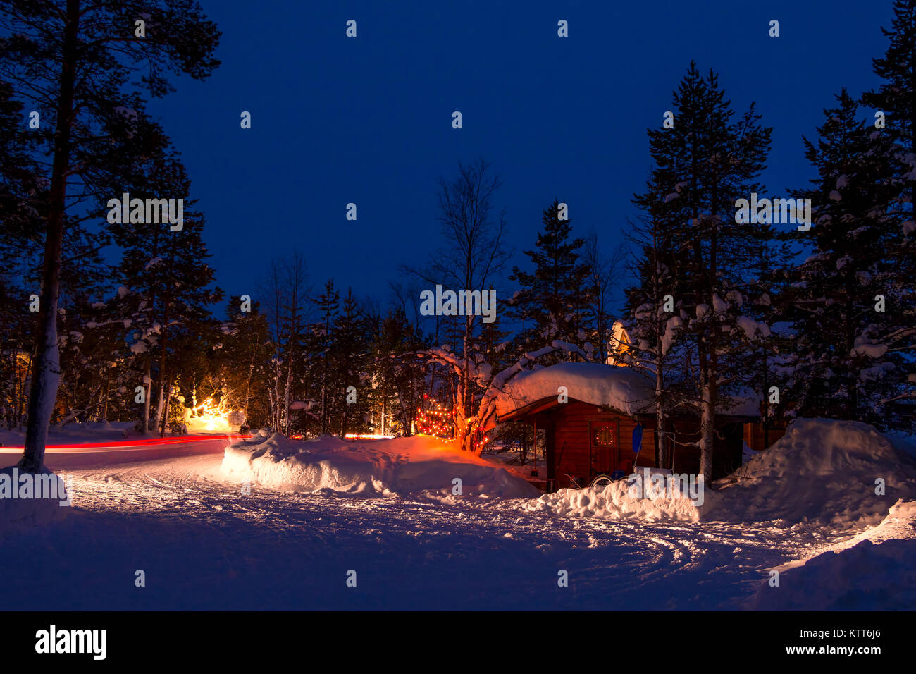 Noche de invierno. Alquiler camping en el bosque. Un montón de nieve. Guirnaldas navideñas y trazas de faros Foto de stock