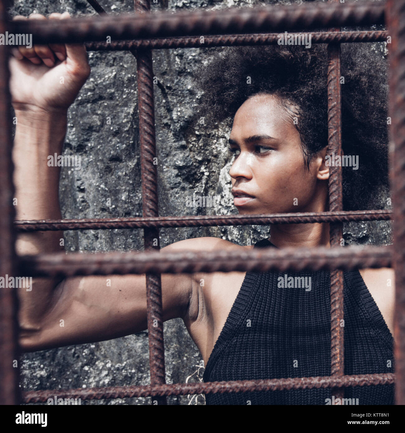 Atleta Afro americana chica con fuertes brazos tras entrenamiento detrás de barrotes de hierro Foto de stock