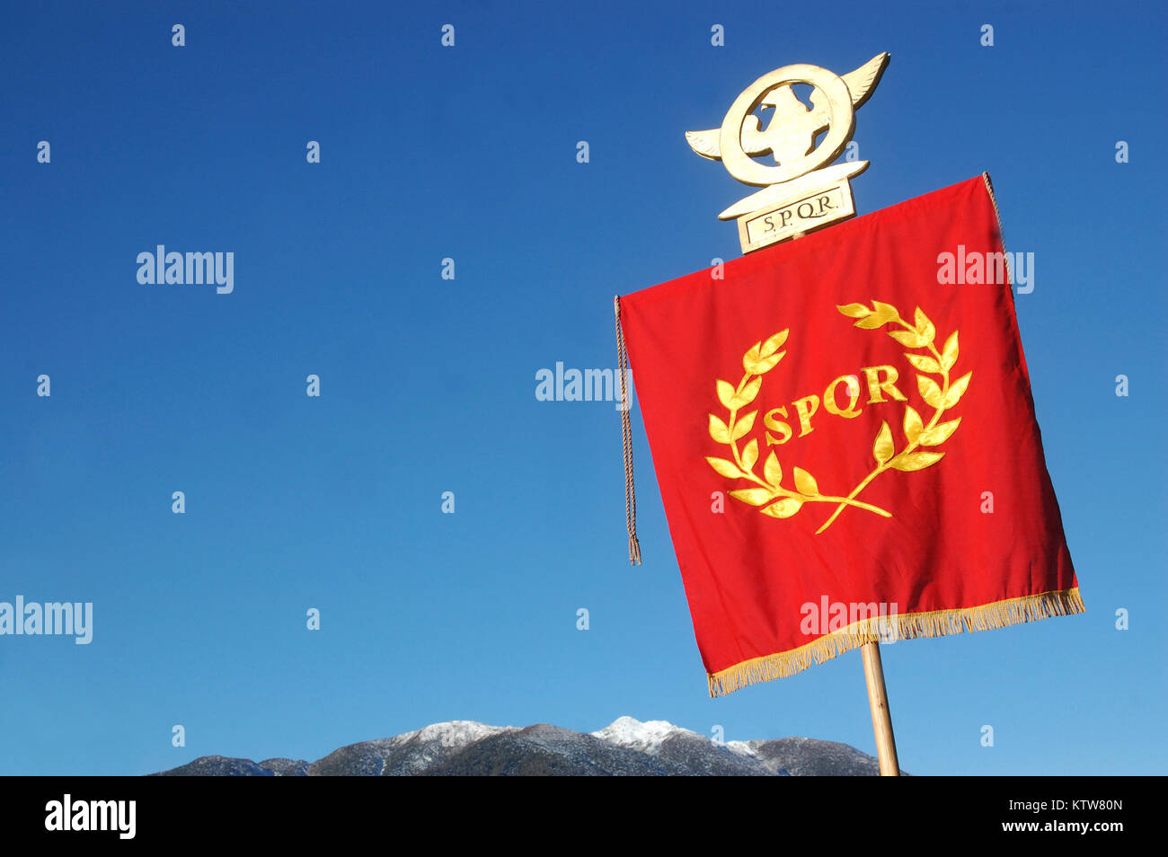 Visualización estándar romana SPQR, contra el cielo azul y los alpes Foto de stock