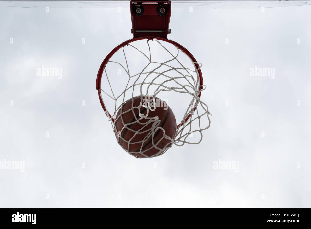En el interior de bola roja canasta de baloncesto, contra el cielo