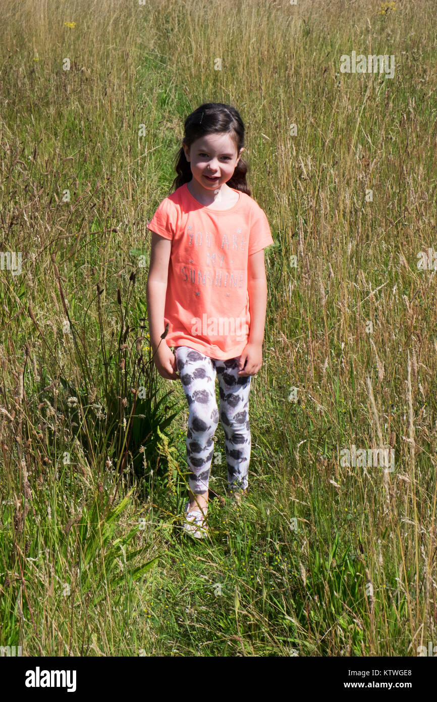 Niña de 5 años caminando a través de una pradera Fotografía de