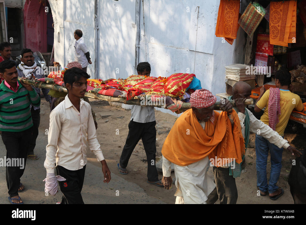 El cuerpo cubierto de un hombre fallecido es llevado en una camilla a través de las calles de Gaya en el sitio de la cremación Foto de stock