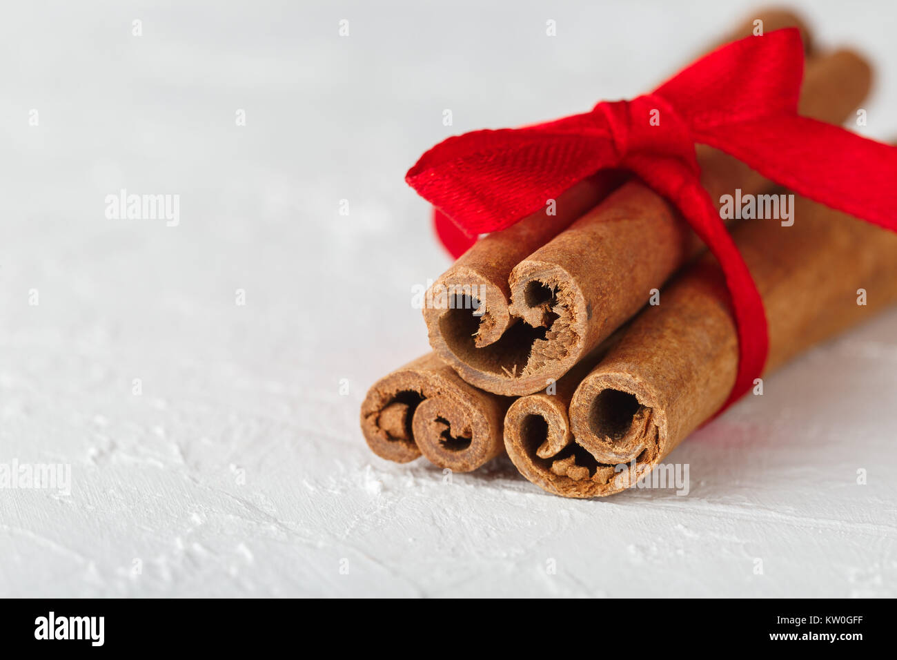 Festivo Canela palos envueltos con una cinta roja sobre fondo de textura  blanca. Macro shot, el enfoque selectivo Fotografía de stock - Alamy