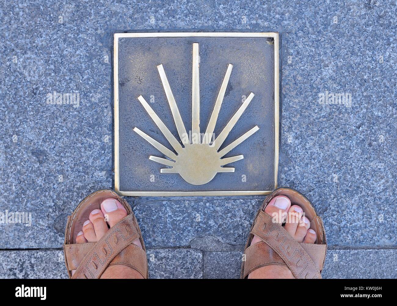 Señal de metal en el asfalto, el Camino de Santiago en España, a los pies  del hombre en sandalias en acera.Desde arriba Fotografía de stock - Alamy