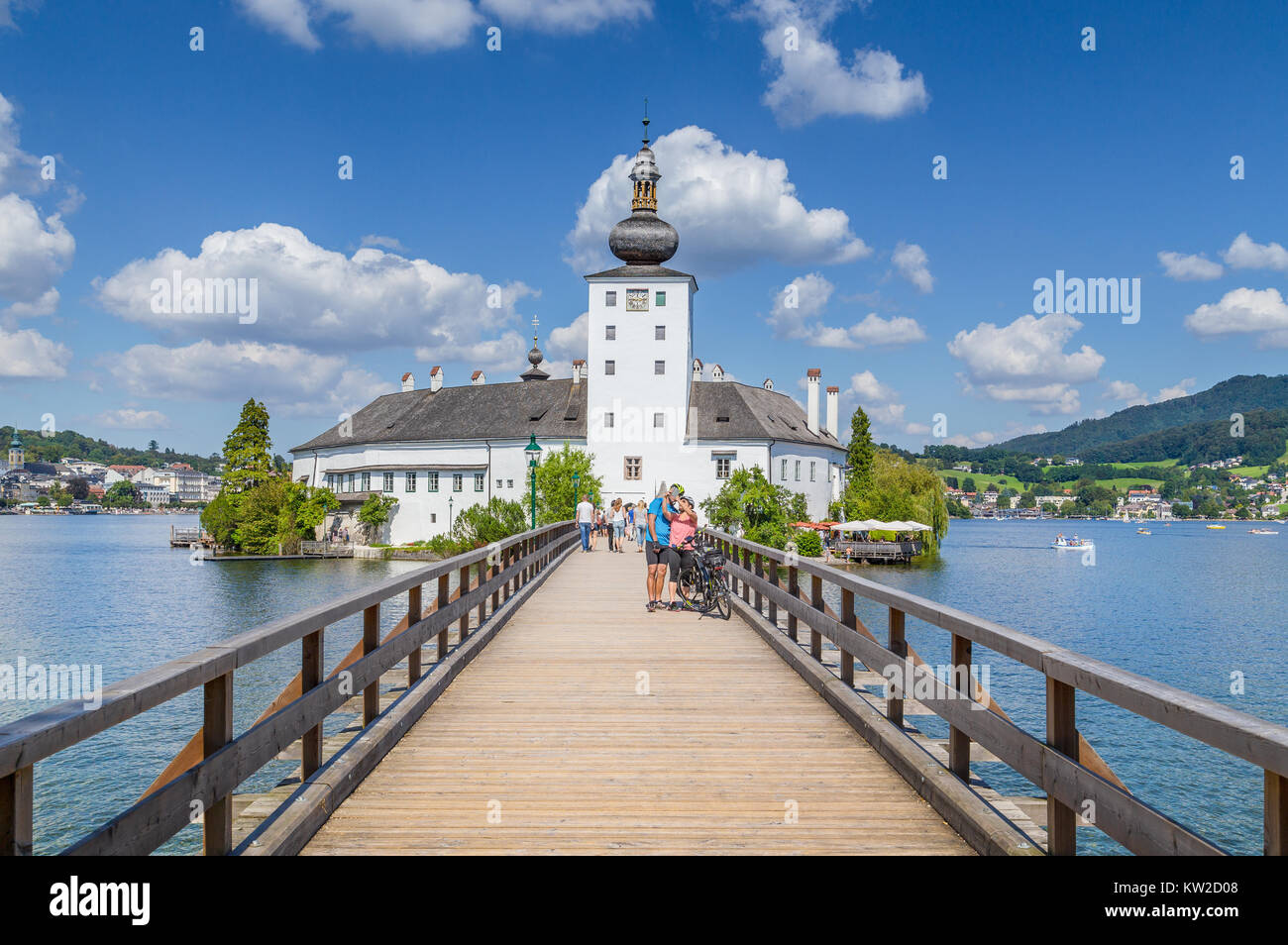 Pareja de turistas tomando un selfie en frente del famoso Schloss Ort en un día soleado con el cielo azul y las nubes en Gmunden, región de Salzkammergut, Austria Foto de stock