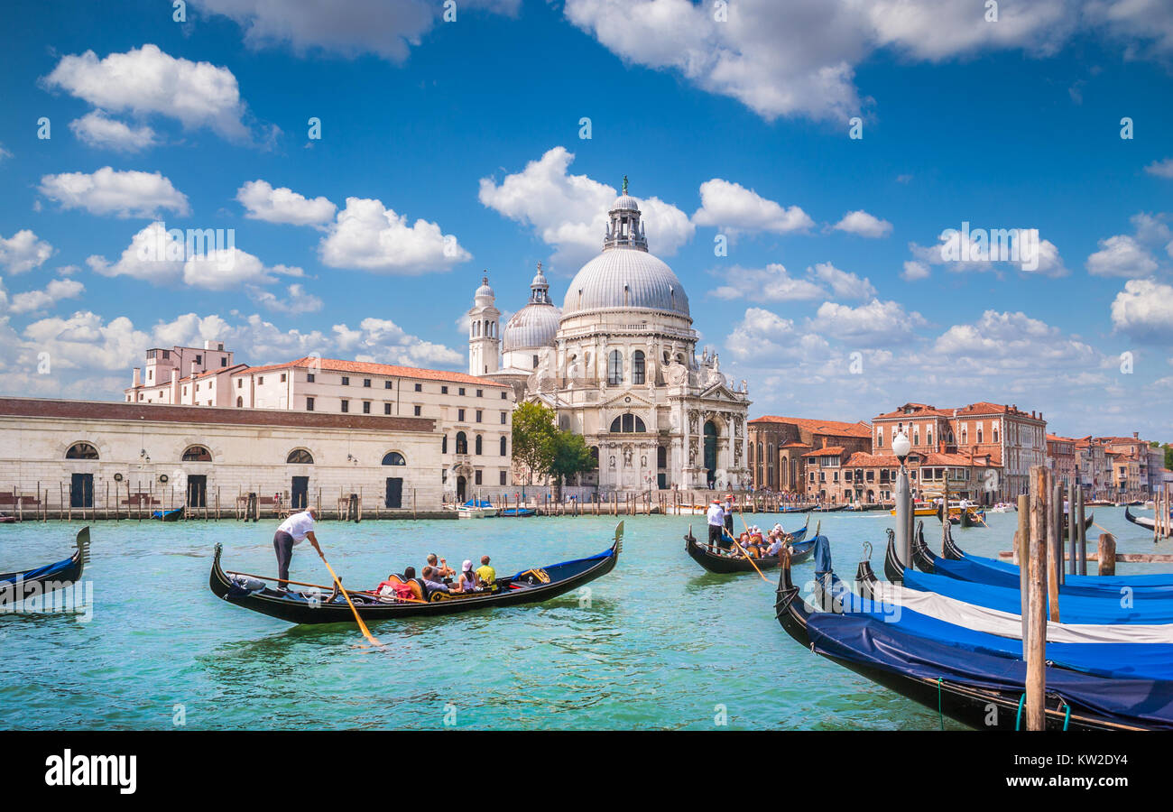 Hermosa vista de las Góndolas tradicionales en el Canal Grande con la histórica Basílica di Santa Maria della Salute al fondo, en un día soleado en Venecia. Foto de stock