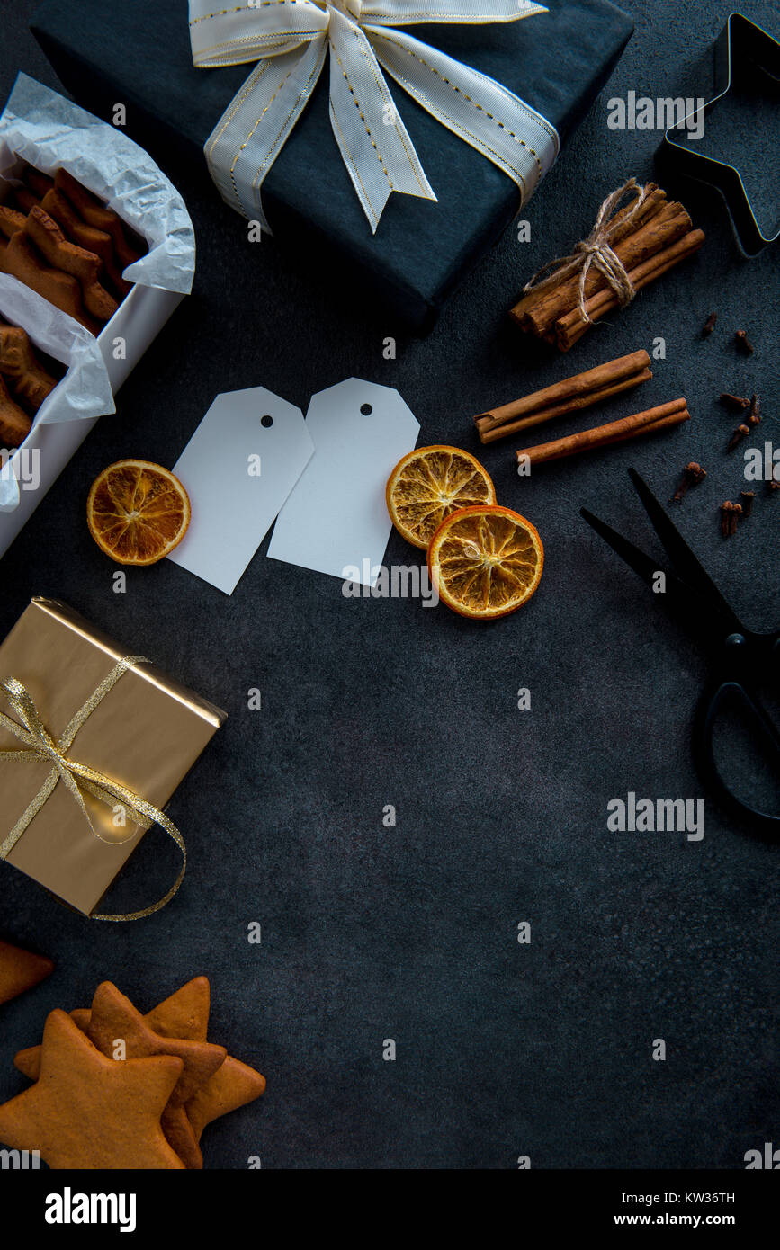 Envoltura de regalos para Navidad. Vista superior de la tabla con las  galletas de jengibre en caja de papel, regalos en elegante negro y oro papel.  Envolver los regalos Fotografía de stock -