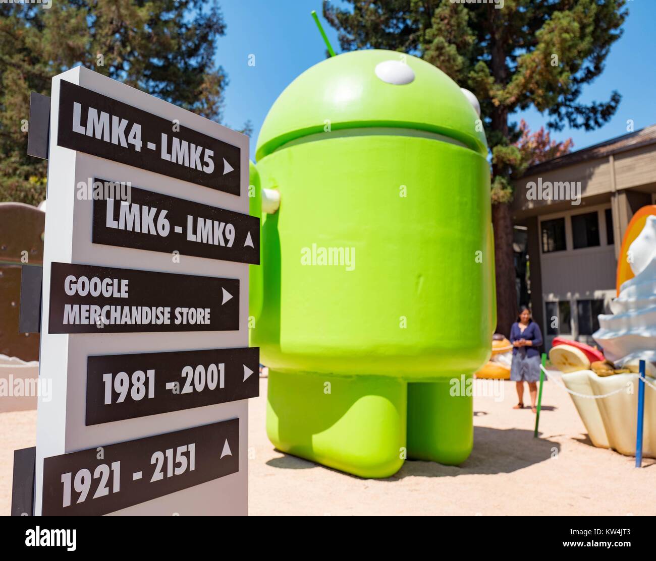 Signo de la Tienda de Google en el Googleplex, sede de la compañía del buscador Google en Silicon Valley, la ciudad de Mountain View, California, con una gran estatua que representa el sistema operativo móvil Android en el fondo, Mountain View, California, 24 de agosto de 2016. Foto de stock