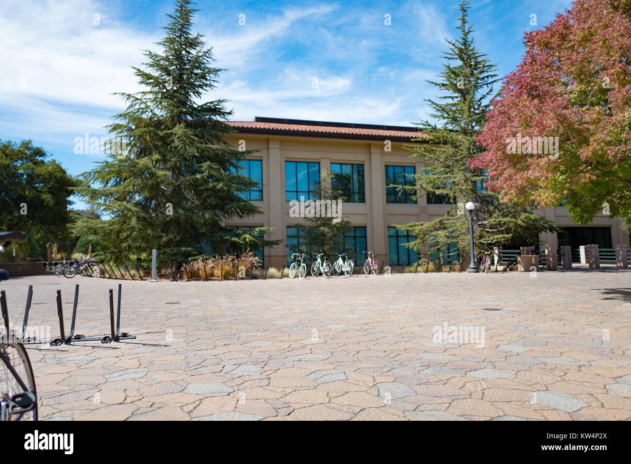 Las bicicletas están estacionados en la plaza empedrada fuera de un edificio de dos pisos, Stanford University, Stanford, California, 3 de septiembre de 2016. Foto de stock