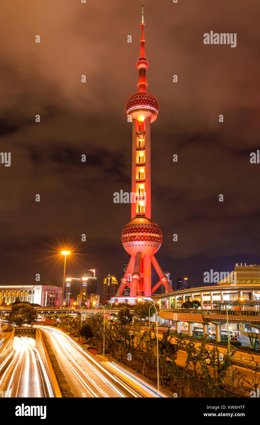 La Oriental Pearl Tower - Una vista de noche de tráfico pesado que fluye pasar la base de la Oriental Pearl Tower rojizo en el centro de Lujiazui, Pudong, Shanghai. Foto de stock