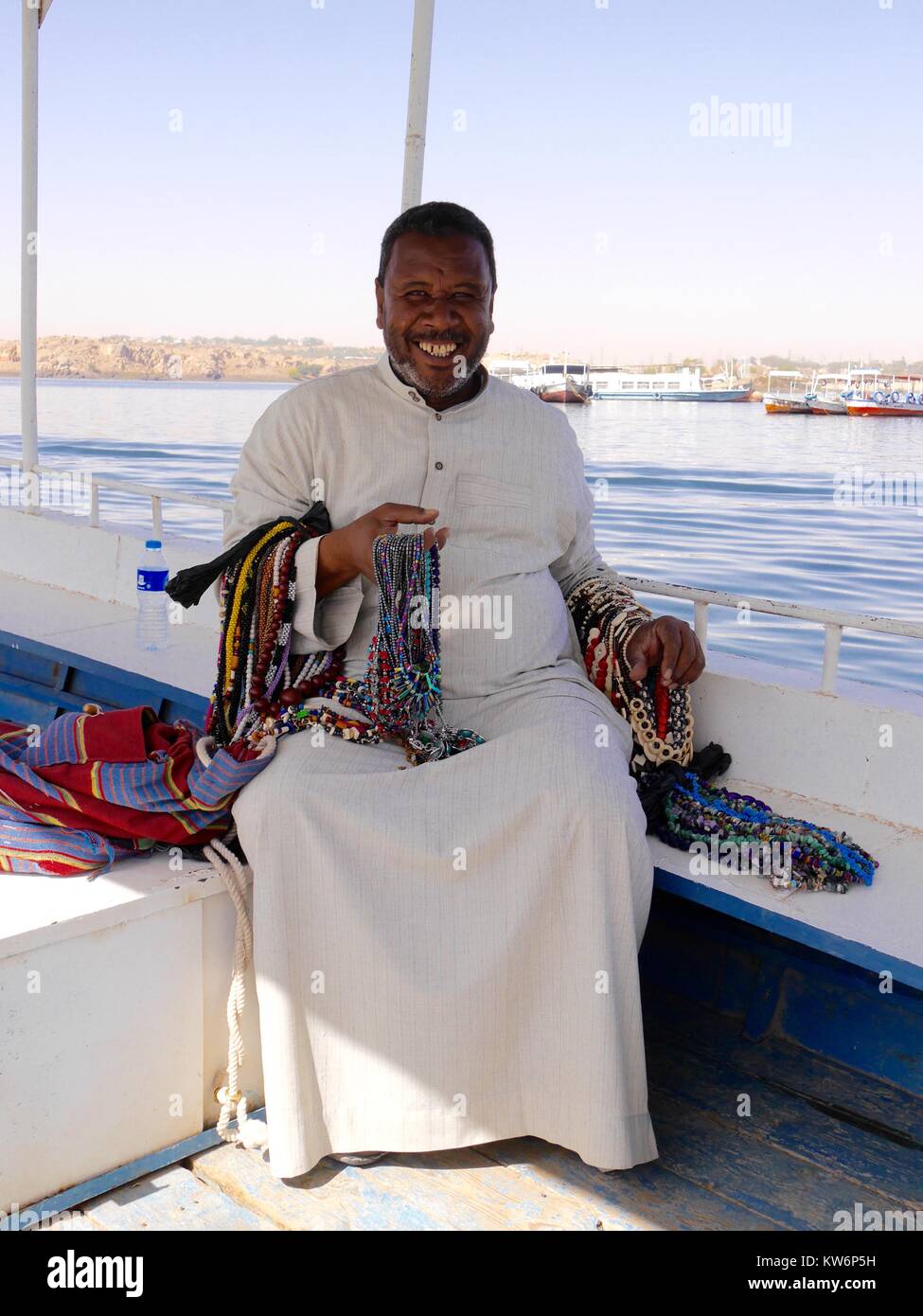Sonriente egipcio con "peligrosas de hermosos collares artesanales en venta sentado en barco sobre el río Nilo Foto de stock