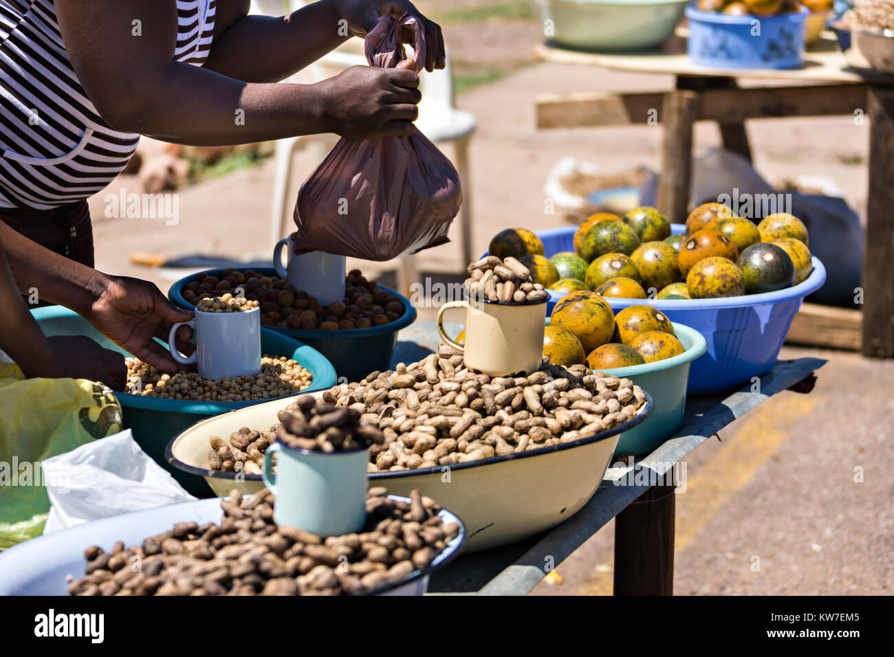 Los vendedores ambulantes africanos dedicados a la venta de cacahuetes, monos naranjas, frijoles, kumquats naranjas Foto de stock