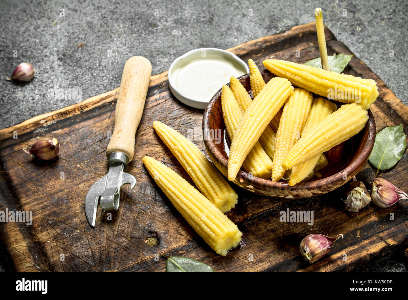 Encurtido de maíz en una jarra sobre una tabla para cortar. Sobre un fondo rústico. Foto de stock
