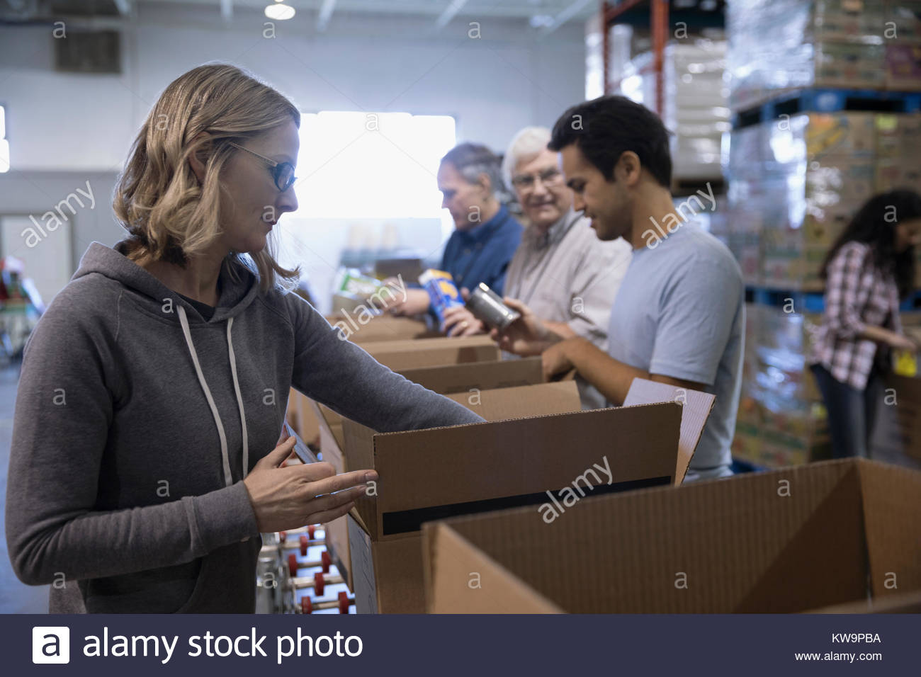 Voluntario Femenino boxeo conservas de alimentos drive en el almacén Foto de stock