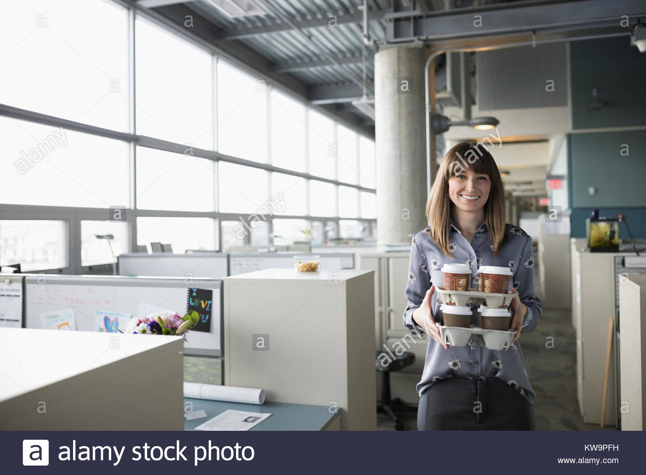 Retrato sonriente,generosa empresaria bandejas de transporte de café en la oficina Foto de stock
