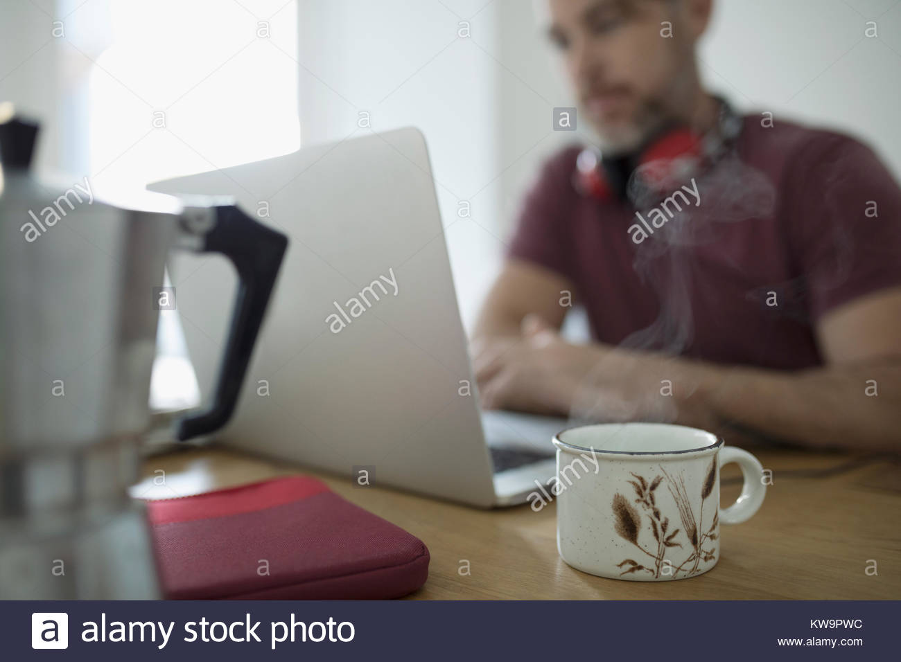 Humeante taza de café y el hombre el teletrabajo,trabajando en equipo portátil Foto de stock