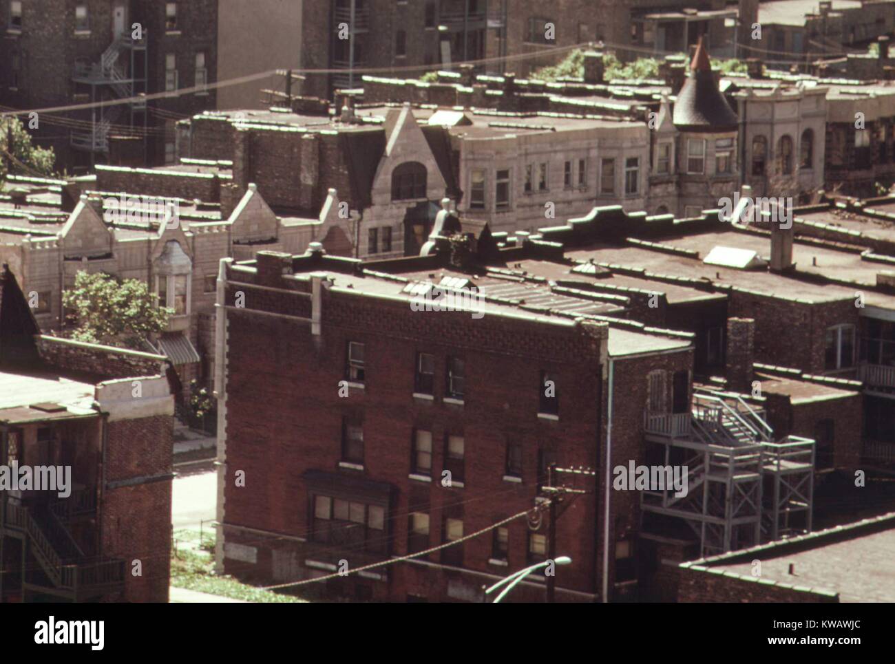 Una vista desde el techo de un edificio vecino, mostrando el callejón al lado y detrás de una fila de casas de la fila de bajos ingresos frente a otra fila, cruzando la calle, con piedra gris y ladrillo rojo hacia los lados y algunos techos triangular en la parte delantera, en el lado sur de Chicago, Illinois, en 1973. Imagen cortesía de los Archivos Nacionales. Foto de stock