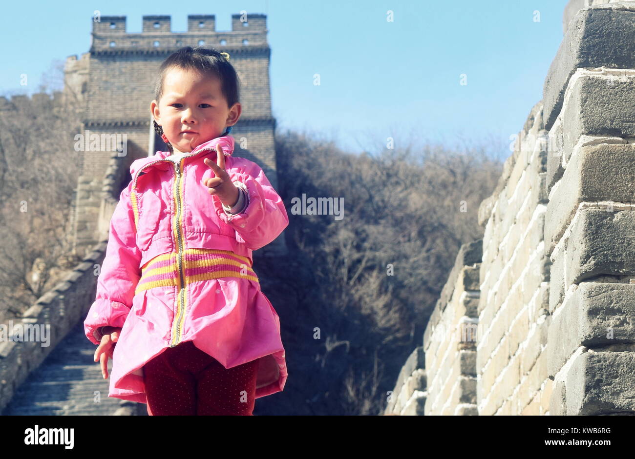 Linda niña china en rosa ropa tradicional plantea en la Gran Muralla de China en frente de una atalaya - sección Mutianyu, Huairou Foto de stock