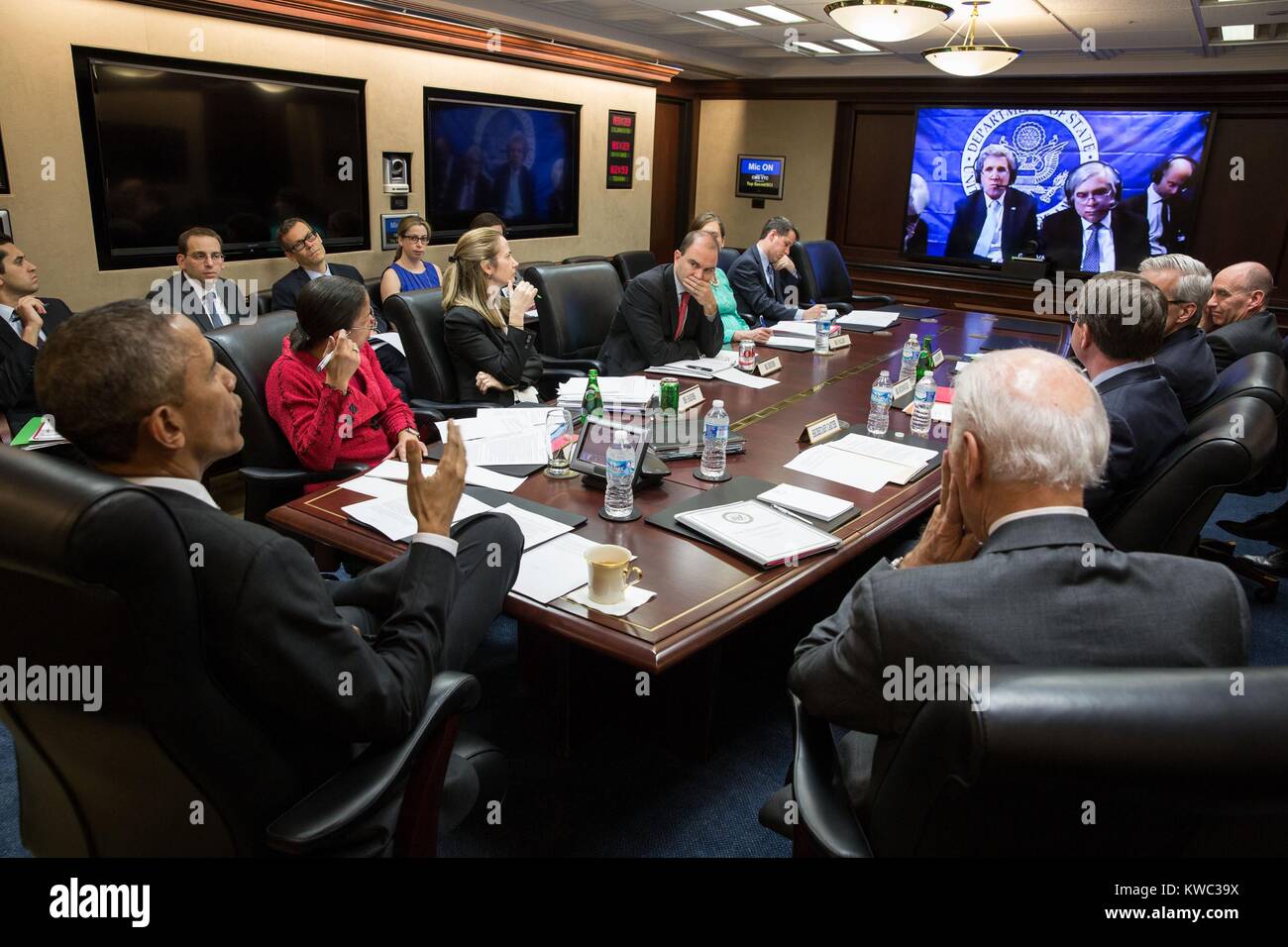 El presidente Obama y su equipo de seguridad nacional en la teleconferencia en el P5+1 negociaciones con Irán. El 31 de marzo de 2015. En la pantalla se Sec. de Estado John Kerry, Sec. de Energía Ernest Moniz y el equipo negociador de Estados Unidos en Lausana, Suiza. Susan Rice, la Asesora de Seguridad Nacional lleva una remera roja. (BSLOC 2015 13 270). Foto de stock