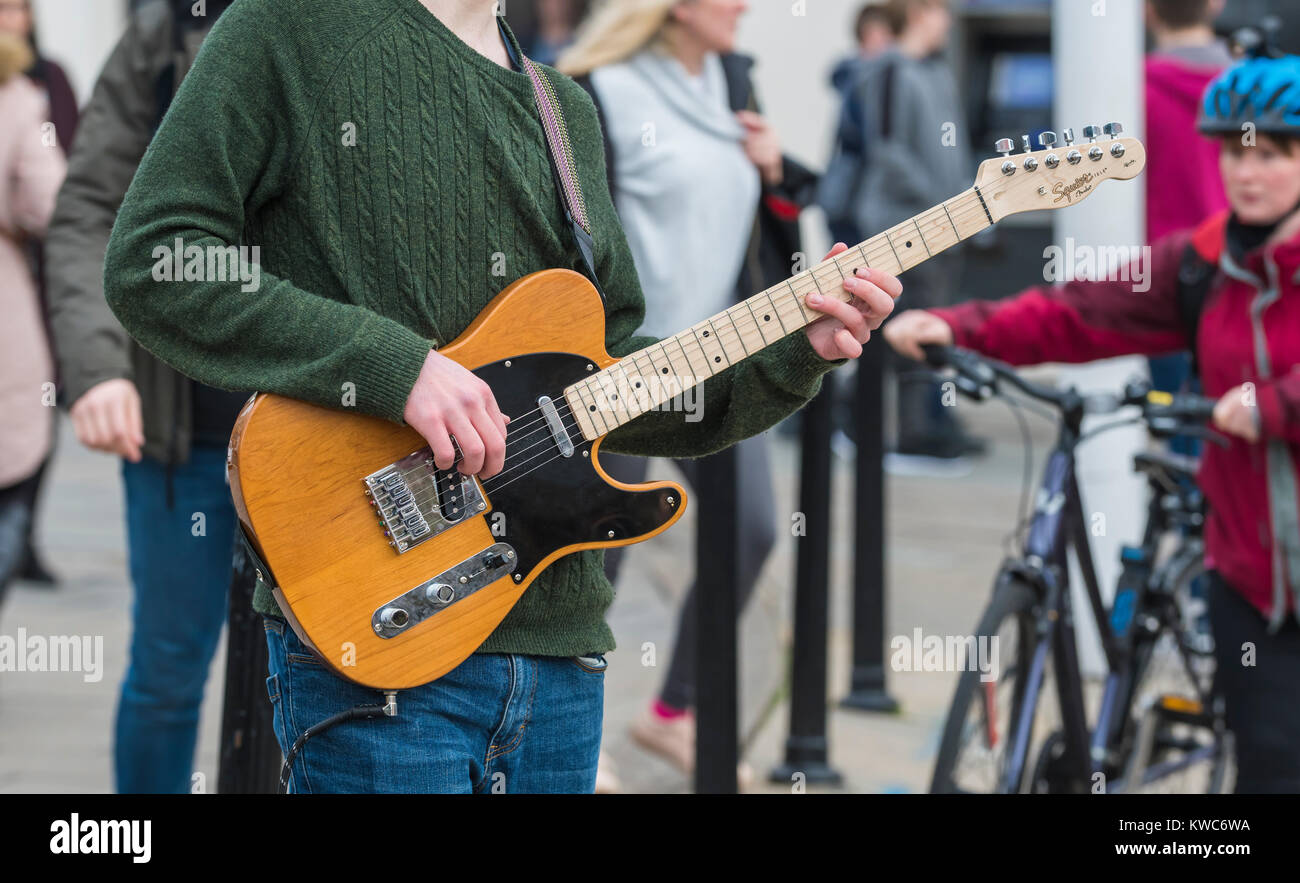 Macho joven músico callejero tocando la guitarra en un día frío en invierno  en la concurrida ciudad de Brighton, East Sussex, Inglaterra, Reino Unido  Fotografía de stock - Alamy