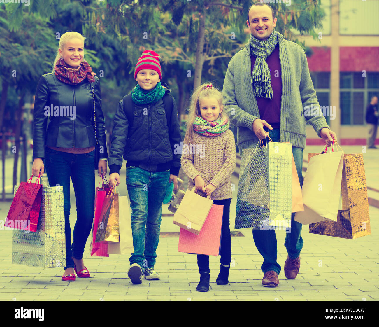 Pareja americana con los niños y las bolsas de compras en las calles de la ciudad Foto de stock
