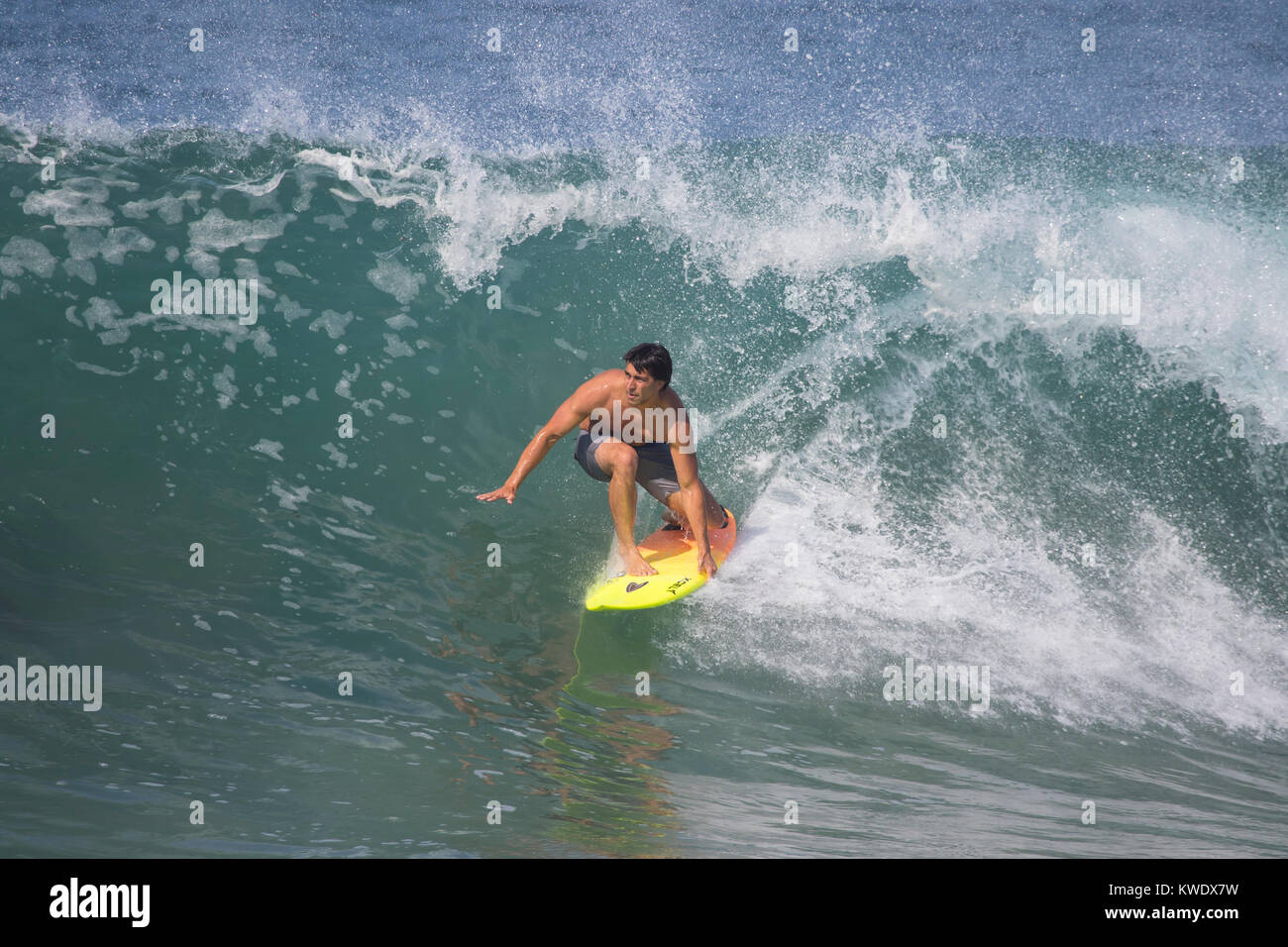 Surfer montando una ola sobre una tabla de surf en la playa de Newport en un día de verano en California, EE.UU. Foto de stock