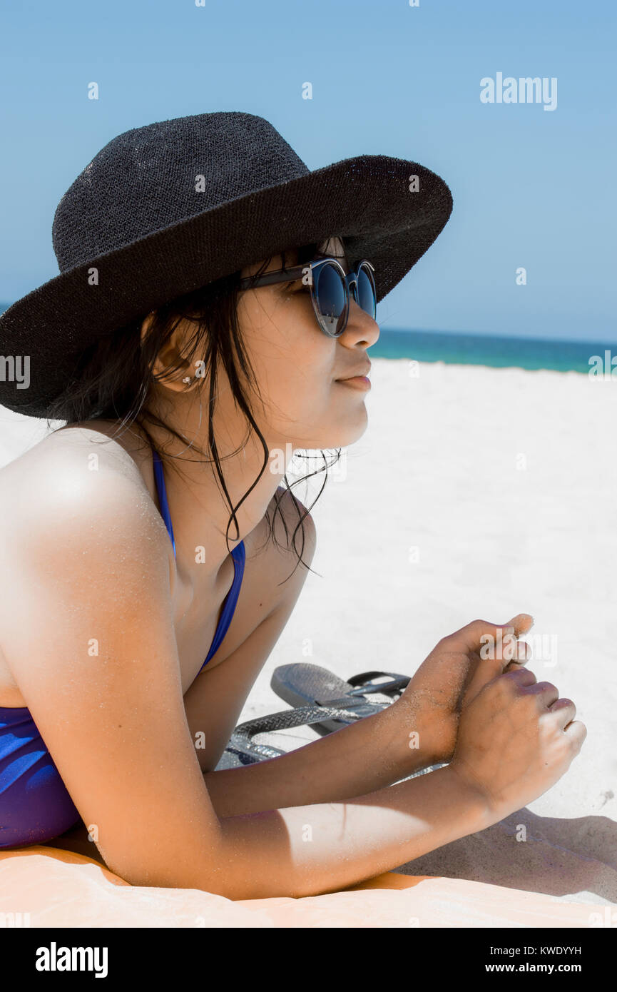 Articulación Poderoso Incorrecto Hermosa chica con gafas de sol y sombrero tumbado en la playa en bikini  Fotografía de stock - Alamy