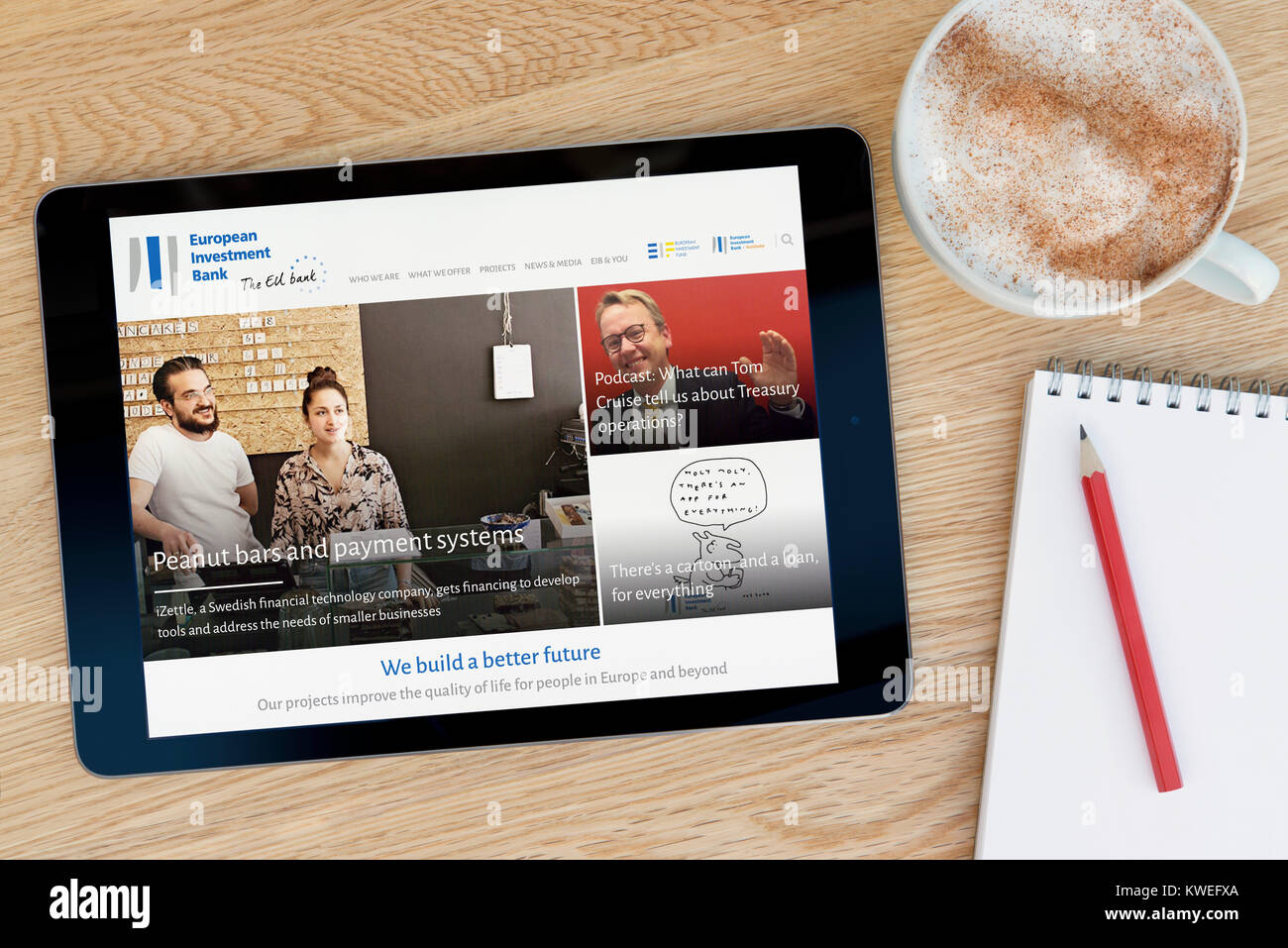 El BEI (Banco Europeo de Inversiones) Sitio web sobre un dispositivo tablet iPad, descansando sobre una mesa de madera junto a una taza de café (Editorial) Foto de stock