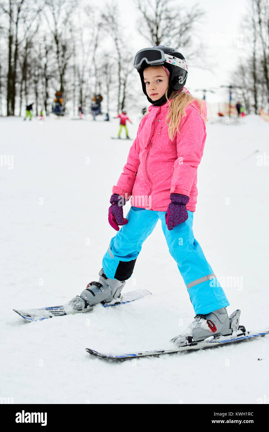Niño a esquiar en las montañas. Chica en el colorido traje y casco seguridad aprendiendo a Deportes invierno para familias con niños pequeños. I Lección de esquí niños