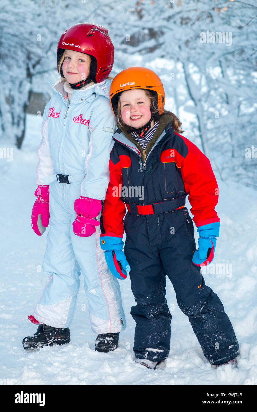 Las niñas, hermanas, de edades comprendidas entre los 5 y 7 años de edad,  portando cascos de esquí freecycle y de seguridad, disfrutar de la nieve  del invierno en su estilo, de