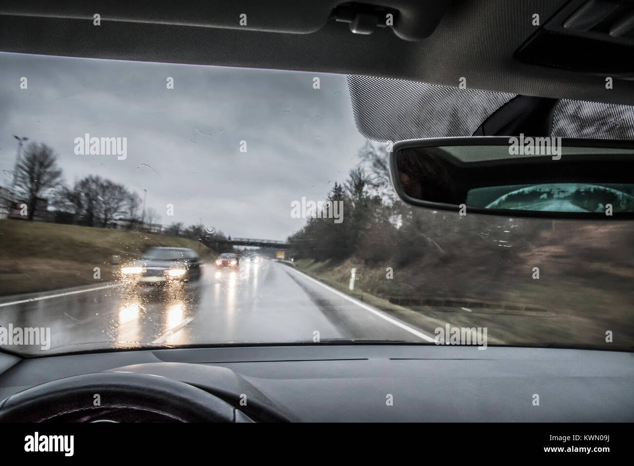 cierre de una máscara blanca colgando del espejo retrovisor de un coche en  la carretera, mientras el conductor no la lleva puesta Fotografía de stock  - Alamy