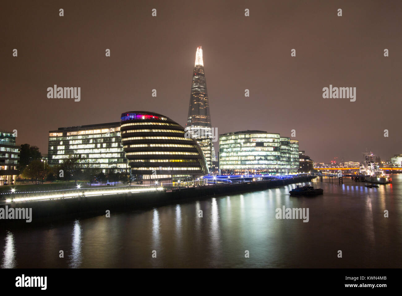 Horizonte de Londres por la noche, incluyendo el Shard y el Ayuntamiento, iluminados a lo largo del río Támesis. Foto de stock