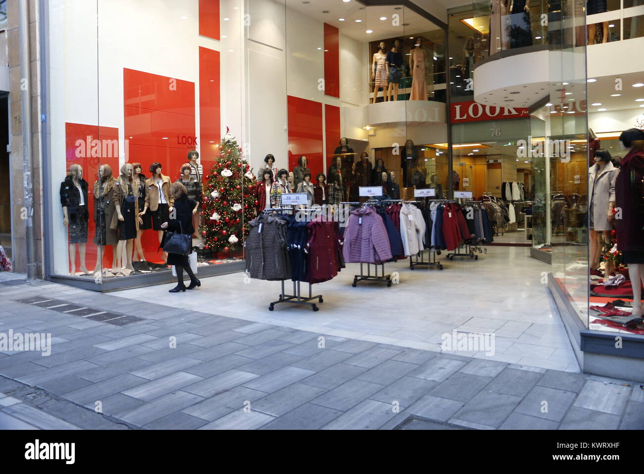 Atenas, Grecia. 18 dic, 2017. Una mujer está mirando en la tienda de ropa para Windows que están en ventas de este período en Aiolou Street. Adornos de Navidad Atenas,