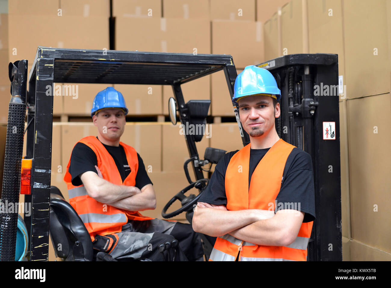 El trabajo en equipo en logística - grupo de trabajadores en una tienda por departamentos con carretillas elevadoras y mercancías Foto de stock