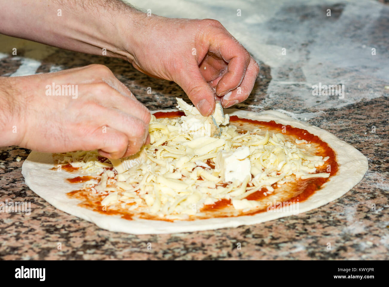Raw original italiana fresca pizza, pasta preparación en estilo tradicional: el chef distribuye el queso. Comida, cocina italiana y cocina concepto. Foto de stock