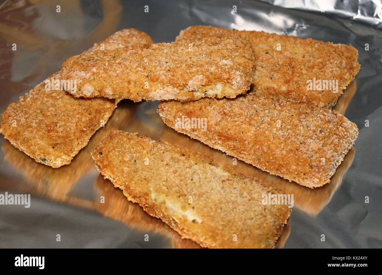 Porciones de pescado congelado maltratadas sobre papel de aluminio en el  horno - listo para hornear Fotografía de stock - Alamy