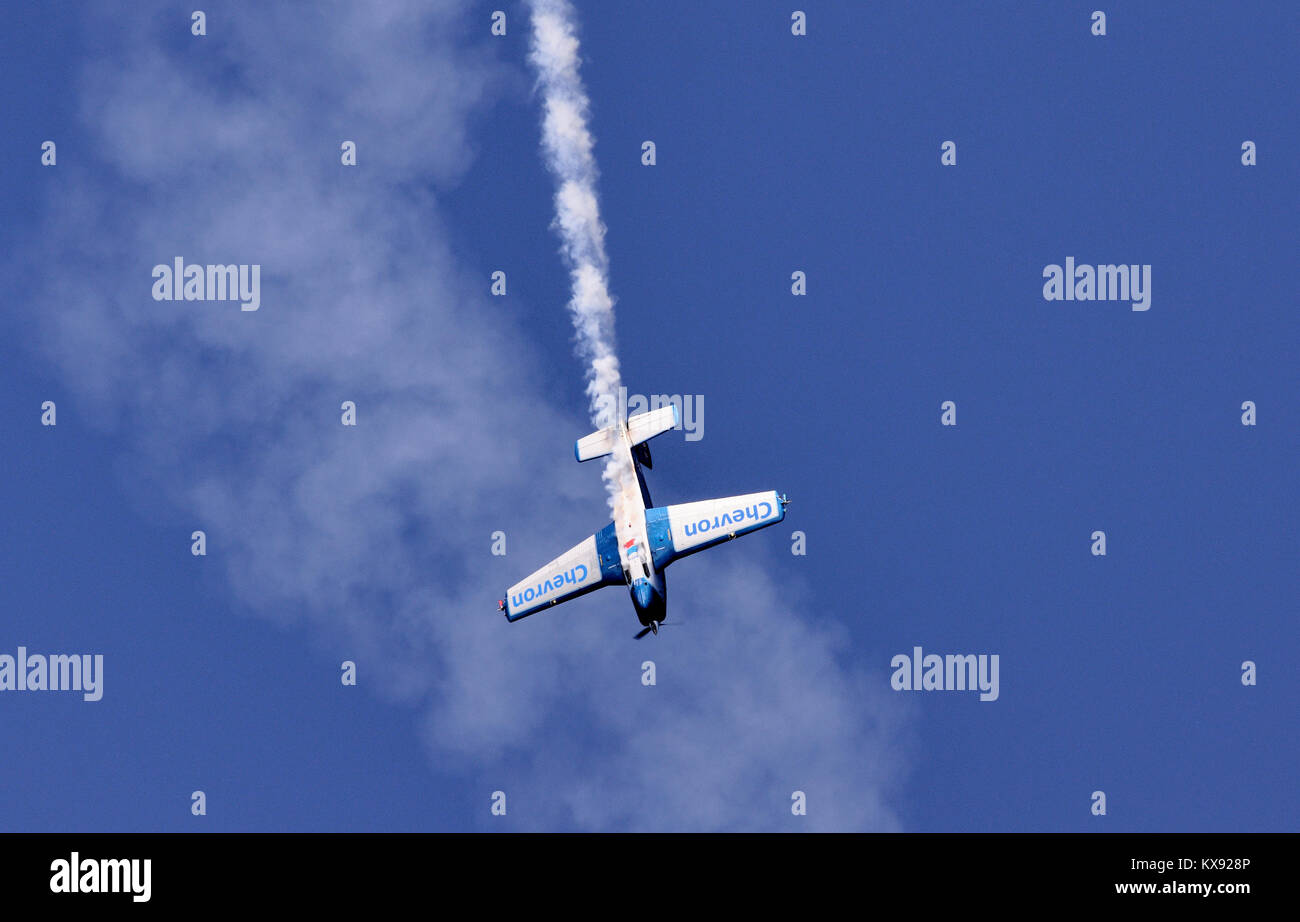 Un pequeño avión realizando maniobras acrobáticas, buceando aquí con humo que se acuesta desde su cola. Foto de stock