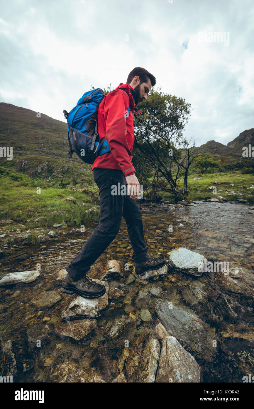 Excursionista con mochila cruzar el arroyo Foto de stock