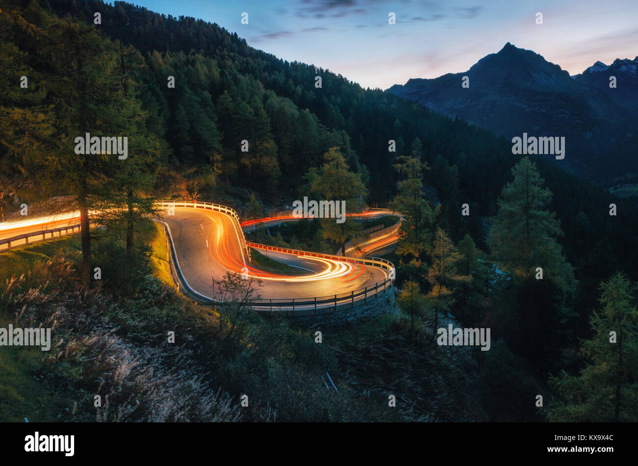 El serpenteante camino de montaña con luz pistas de vehículos en la noche, Maloja Pass, Suiza Foto de stock