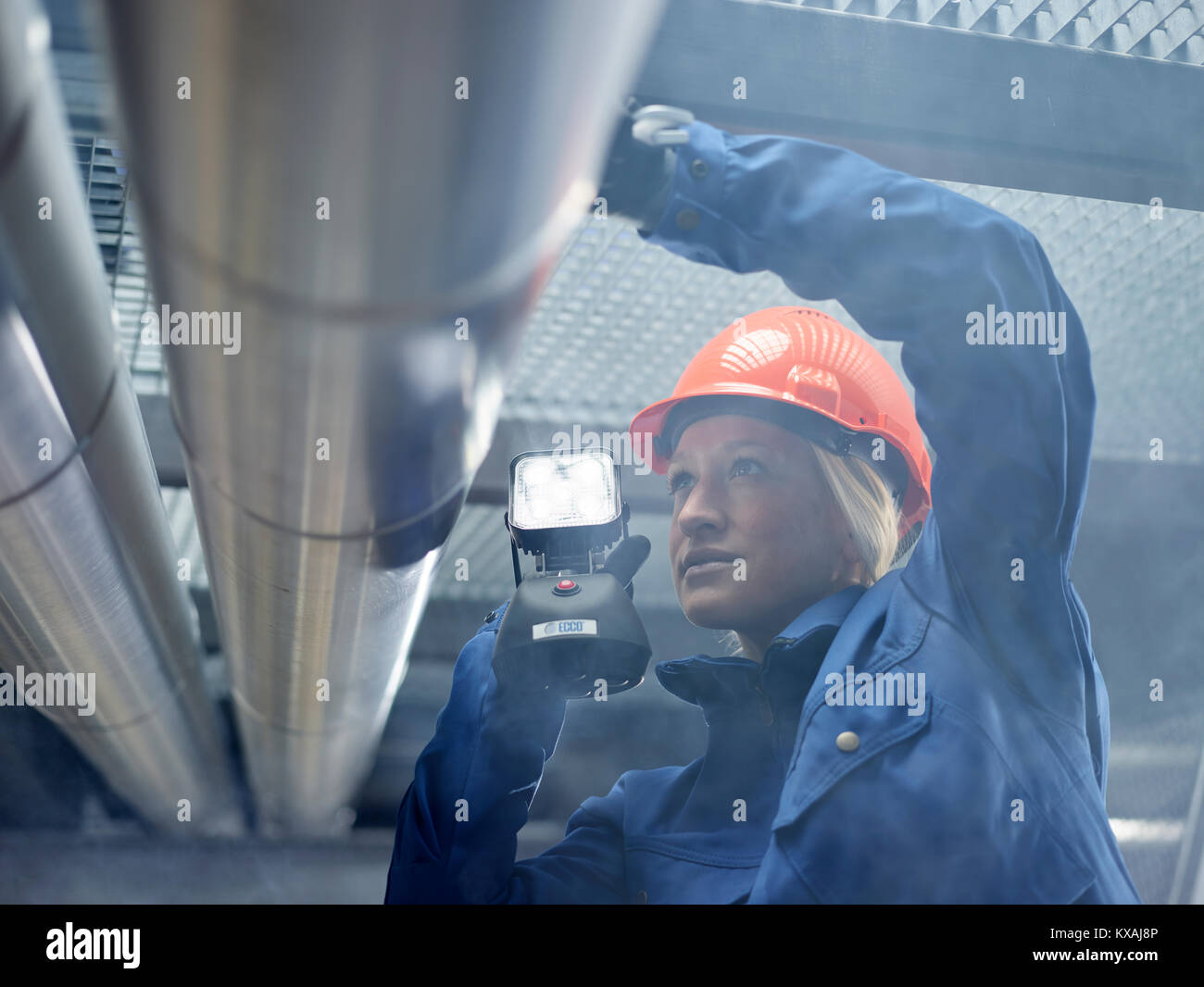 Técnico, el montador con casco y lámpara naranja inspeccionó tuberías, Wattens, Tirol, Austria Foto de stock