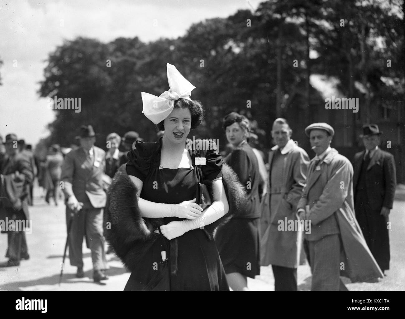 Gire la cabeza para mirar una moda señorita vestida con su elegante vestido y sombrero en el Royal Ascot 1937 Foto de stock