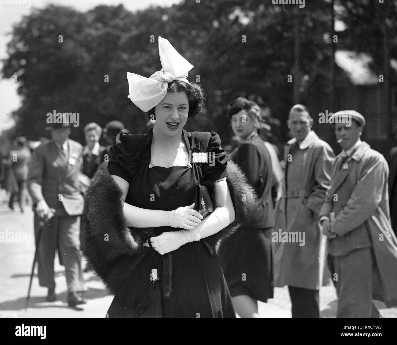 Gire la cabeza para mirar una moda señorita vestida con su elegante vestido y sombrero en el Royal Ascot 1937 Foto de stock