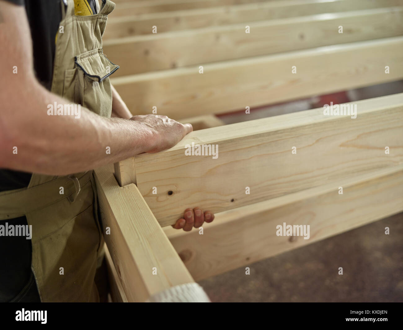 Las manos del hombre conectar dos vigas de madera con ranura y lengüeta de conexión de una construcción de madera, Austria Foto de stock