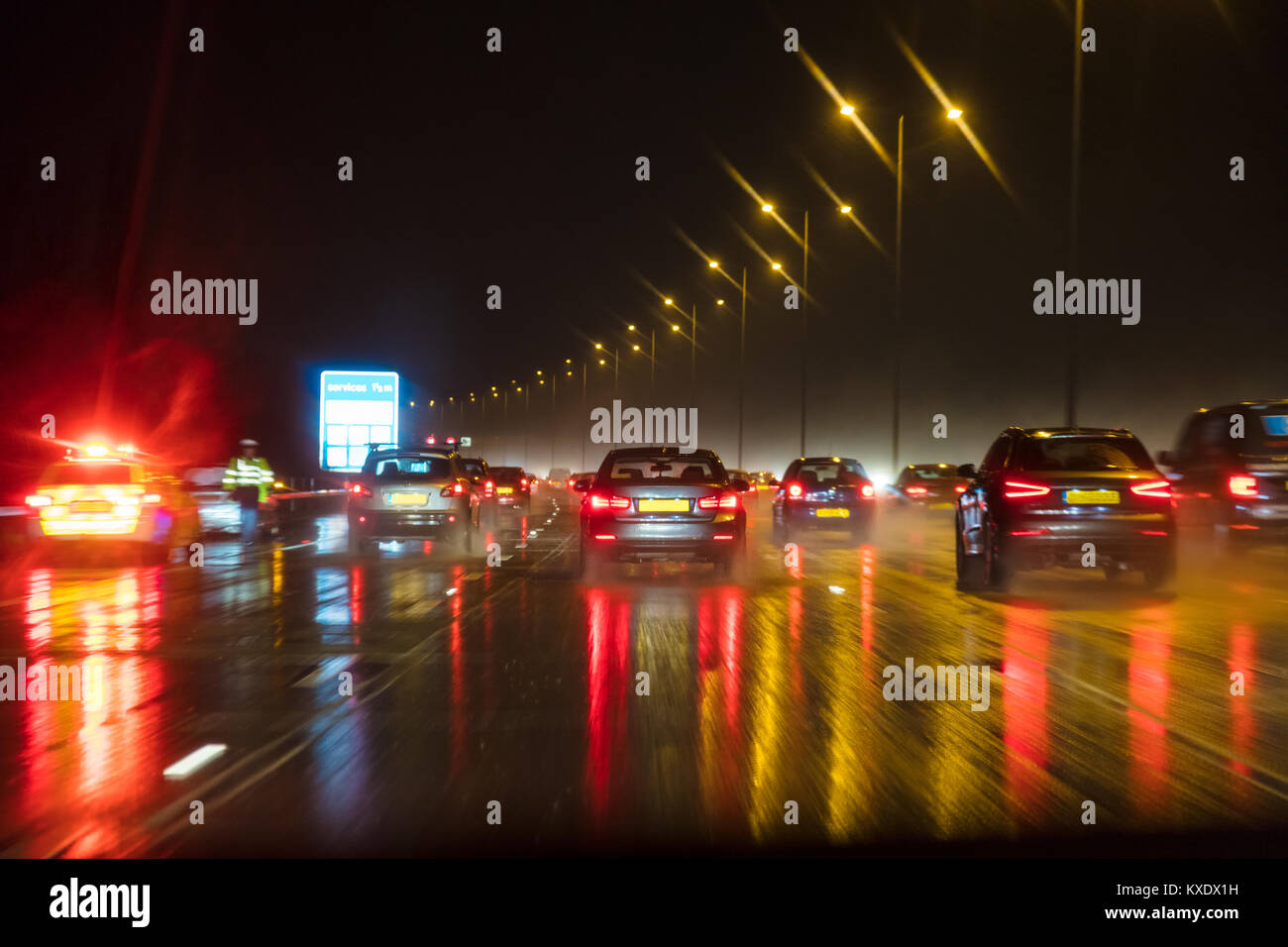 Fotografía borrosa de movimiento de tráfico en la noche en la lluvia en una autopista británica con el policía y coche Foto de stock