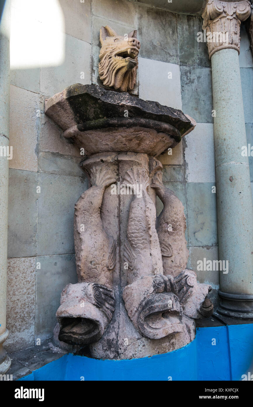 Fuente de agua de piedra de mármol, con una cabeza de lobos en la parte  superior y el pescado en cascada hacia la base, columnas decorativas, y el  interior azul, en Guanajuato